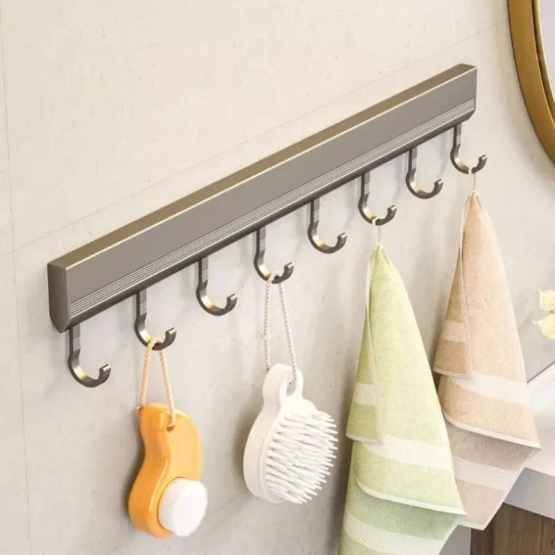 Wall-mounted hook rack with various items hanging from it on a light-colored wall.