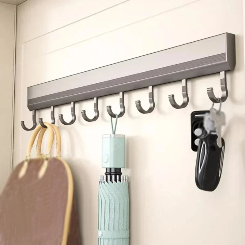 Wall-mounted hook rack with various items hanging on it against a white wall.