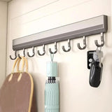 Wall-mounted hook rack with various items hanging on it against a white wall.