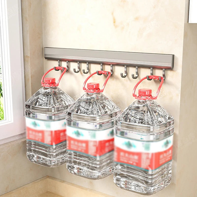 Three large water bottles with red labels hanging on a wall-mounted hook rack.
