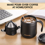 Black coffee maker with a mug on a desk next to a laptop